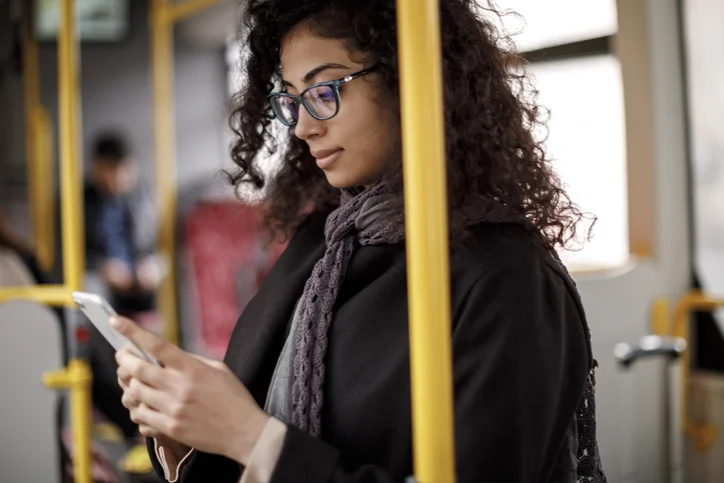 Mulher no ônibus, mexendo no celular. 