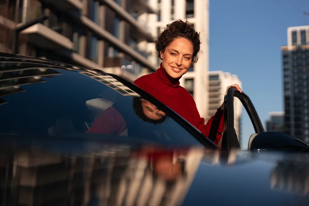 Imagem de uma pessoa entrando em um carro elétrico sedan