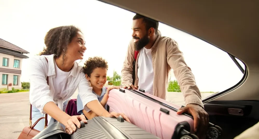 Imagem de uma família no carro arrumando a bagagem para viajar