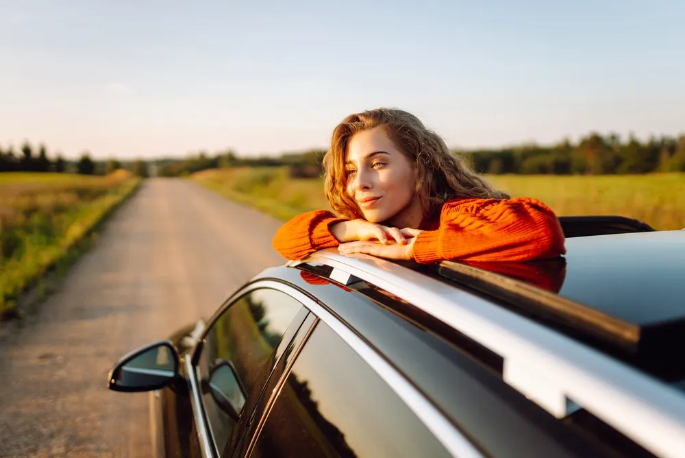 Imagem de uma mulher na estrada representando os melhores carros para viajar