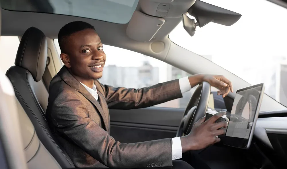 Quanto gasta um carro elétrico por mês x carro a combustão? Quanto gasta um carro elétrico por mês? Imagem de uma pessoa dirigindo um carro elétrico