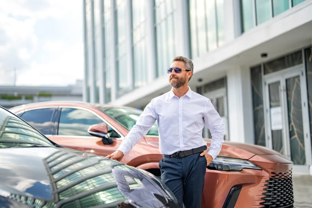 Imagem de um homem parado em frente a modelos de SUvs de luxo no Brasil