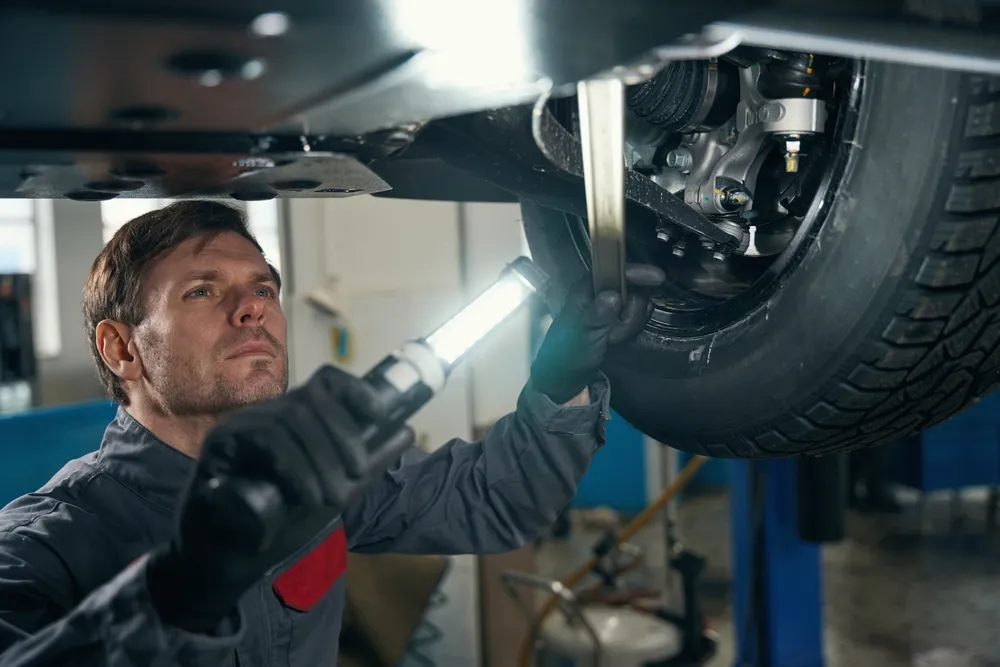 Imagem de um mecânico checando a suspensão automotiva