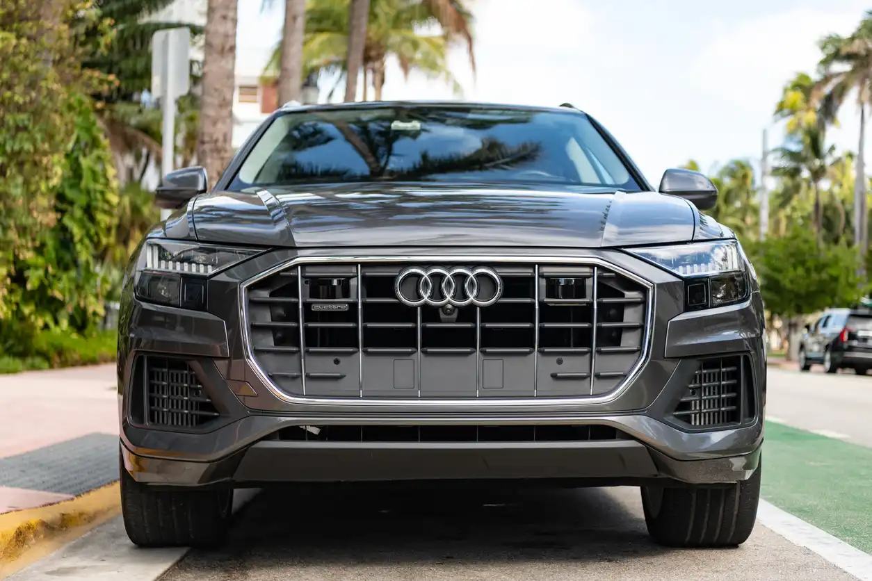 Carro Audi Q5 preto estacionado na rua, com árvores ao fundo, em um dia ensolarado.