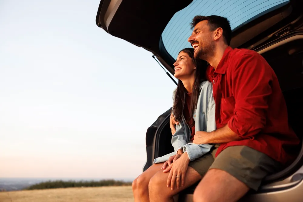Imagem de um casal com seu carro zero sem juros