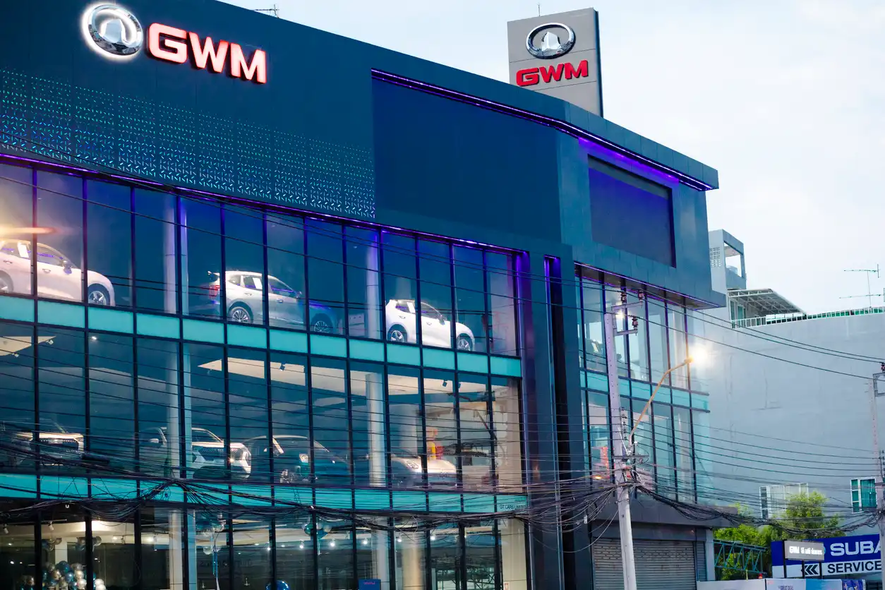 Fachada de uma concessionária GWM com carros expostos na loja e sinalização visível na cidade, destacando a marca GWM e automóveis na vitrine.
