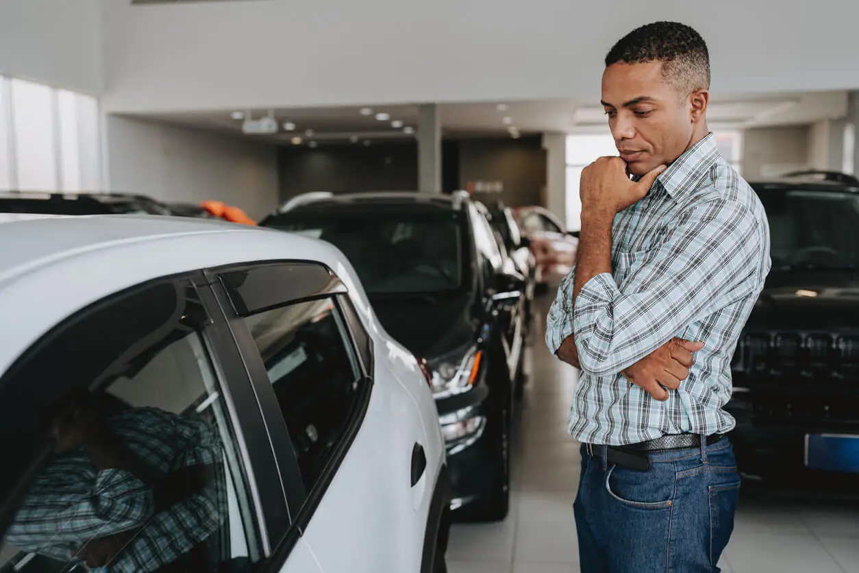 homem em duvida de qual carro escolher