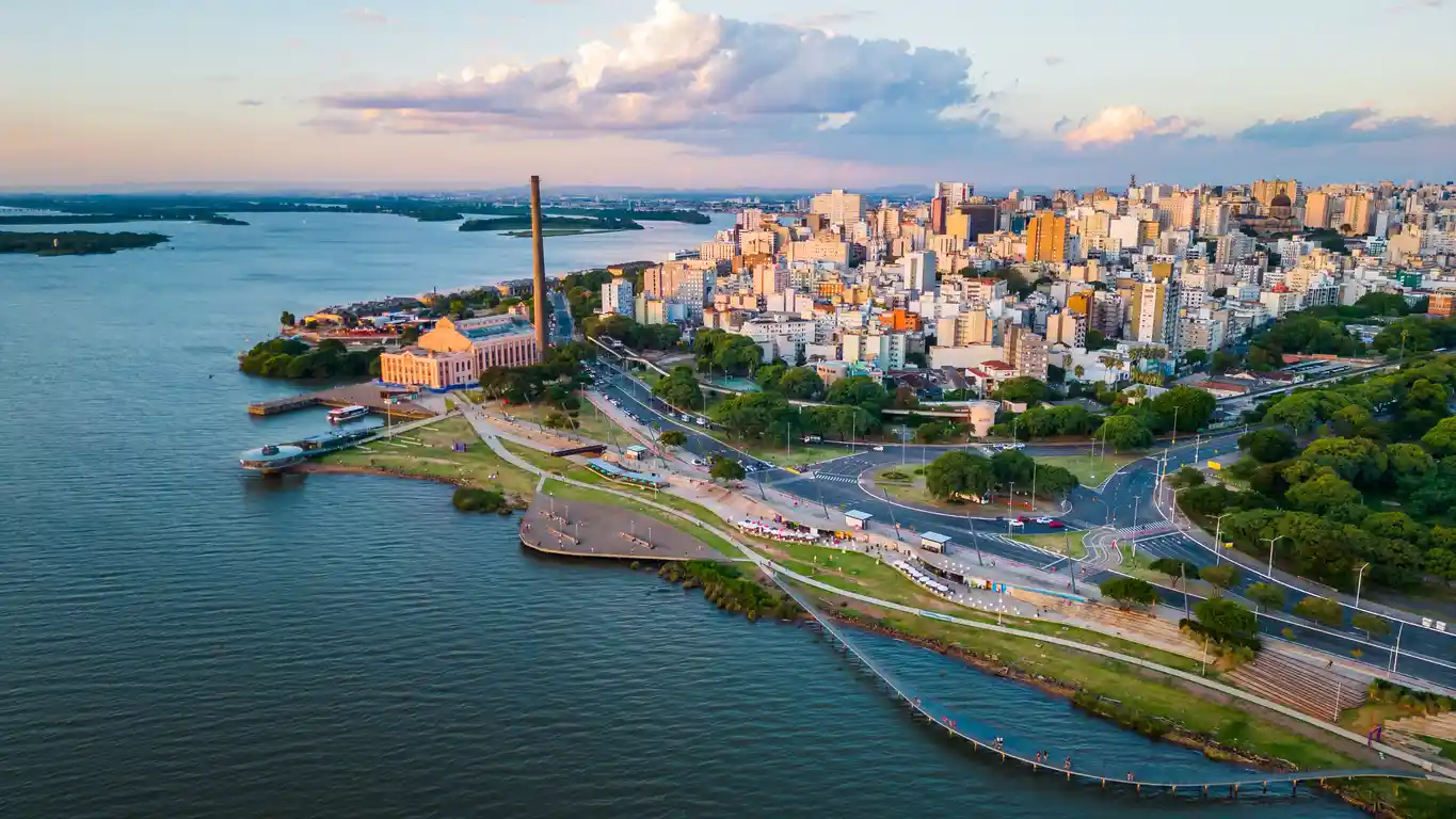 IPVA RS: valor, tabela de alíquotas, calendário e descontos Paisagem urbana de Porto Alegre no bairro Gasômetro, com vista do Lago Guaíba, arquitetura moderna, tráfego rodoviário e áreas verdes ao entardecer.