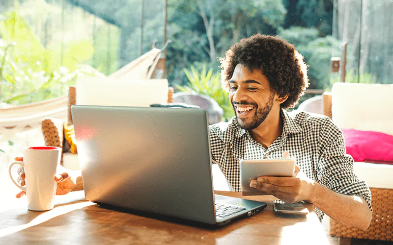 homem sorrindo e sentado na frente do computador. 