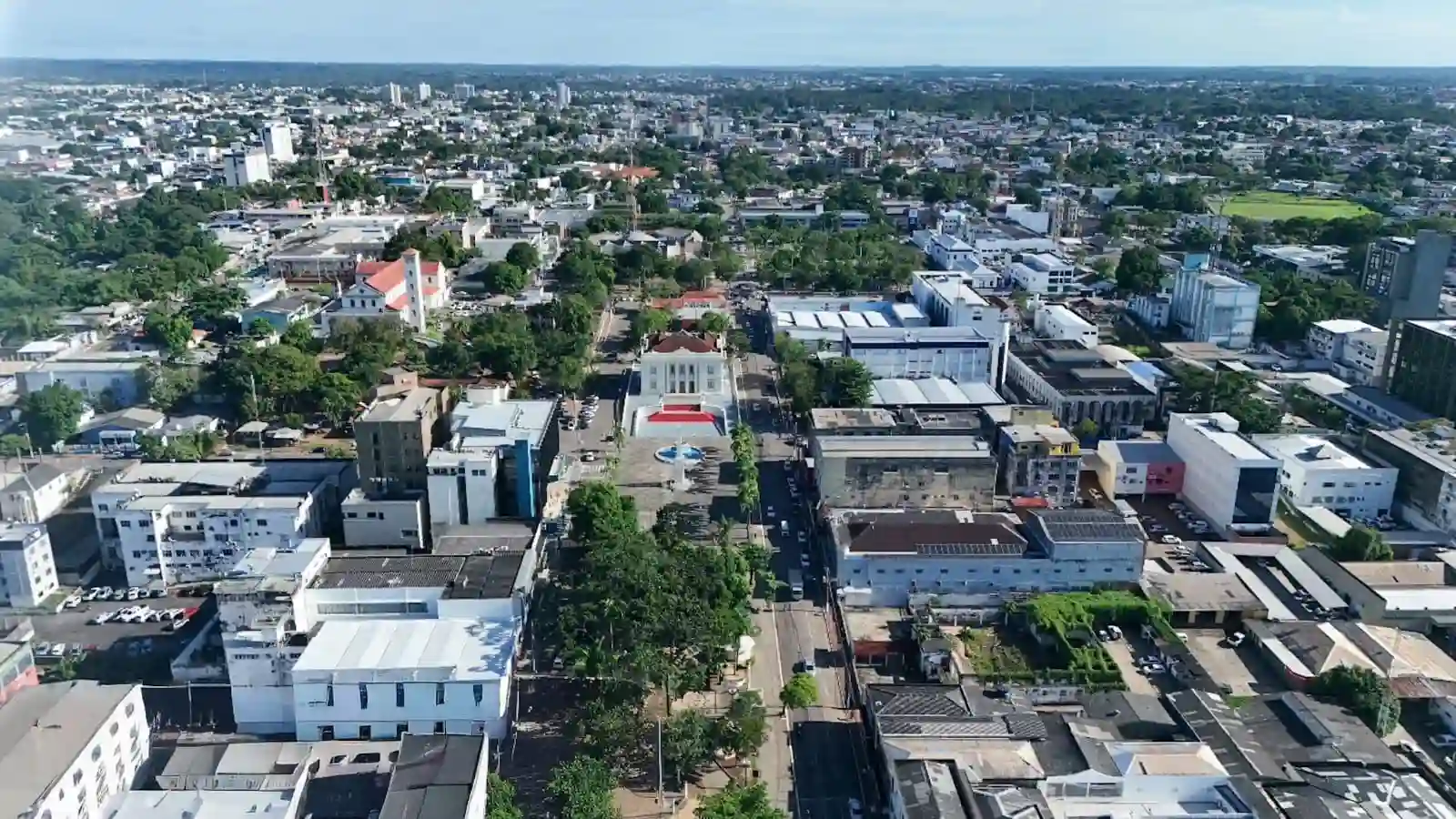 Vista aérea do centro de Rio Branco, Acre, mostrando ruas, prédios comerciais e áreas verdes, destacando a urbanização da cidade.